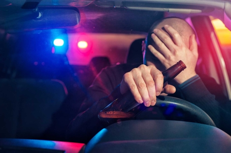 a man being pulled over putting his head in his palm, holding  a beer.