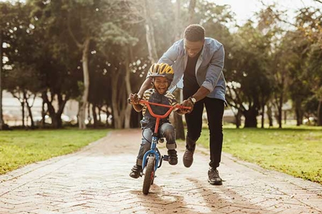 a dad teaching their son to ride a bike.